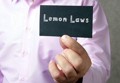 Hand holding a card reading Lemon Laws, discussing California Lemon Law and Federal Warranty for San Jose car buyers.