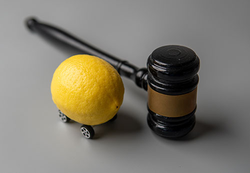 Gavel next to a lemon on wheels, symbolizing Federal Warranty Law and lemon law cases.