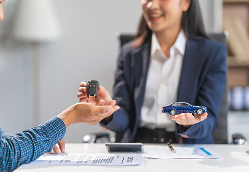 Attorney giving a client a car key and a toy car, emphasizing Magnuson-Moss Warranty Act and prompt legal action.