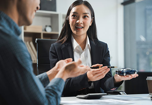 Lawyer shows client a toy car, discussing Lemon Law steps for a defective car in a consumer protection case.