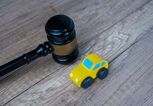 Gavel and a small yellow car, symbolizing a Lemon Law case.
